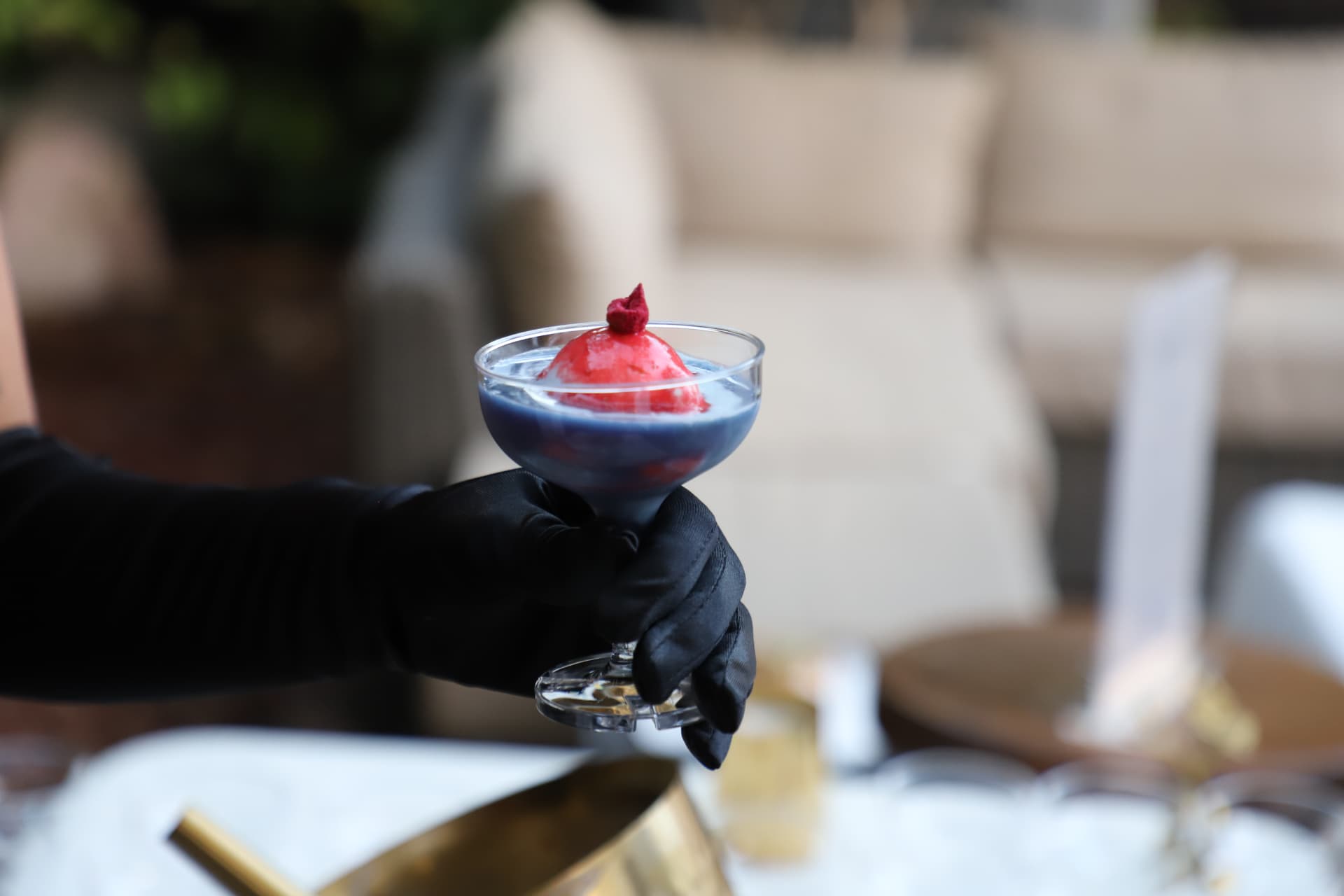 A gloved hand holding a Raspberry Butterfly Blue Fogato affogato